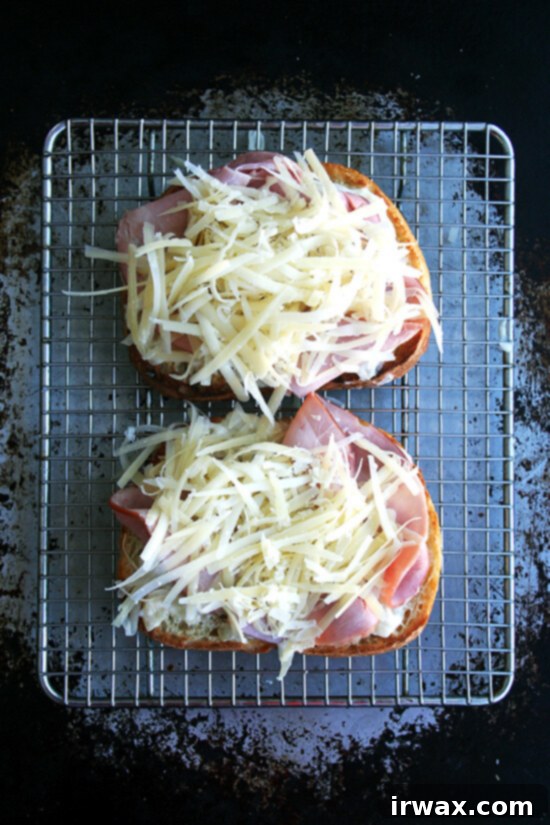Κροκ Μονσιέ με αυγά ποσέ 5 Croque Monsieur υπό κατασκευή: Δύο φέτες τοστ με μπεσαμέλ, ζαμπόν και τυρί σε σχάρα τοποθετημένη σε ταψί.