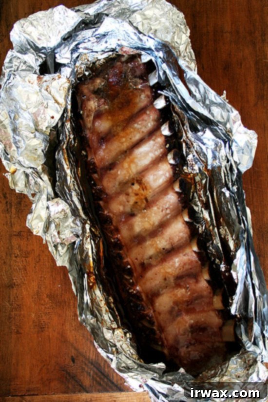 Baby Back Ribs Ολόκληρο ράφι baby back ribs ψημένα στον φούρνο σε αλουμινόχαρτο πάνω σε ξύλινη επιφάνεια