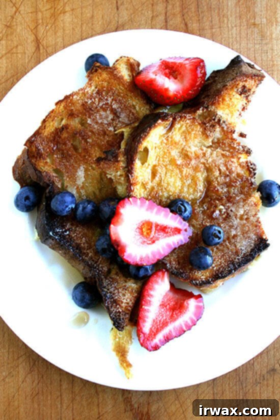 Αυτό είναι το πιο εύκολο French Toast που θα φτιάξετε ποτέ, και πιστεύω ότι είναι και ένα από τα καλύτερα. Έχει τραγανή εξωτερική επιφάνεια και είναι αφράτο, αλλά σε καμία περίπτωση υγρό, στο εσωτερικό. Βγαίνει από το φούρνο καυτό, αρκετό για τουλάχιστον τέσσερις ανθρώπους. Το ψημένο French Toast από το προηγούμενο βράδυ είναι ιδανικό για ένα brunch που μπορείτε να ετοιμάσετε από πριν. // alexandracooks.com Ένα πιάτο με French Toast από το προηγούμενο βράδυ, γαρνιρισμένο με μούρα.