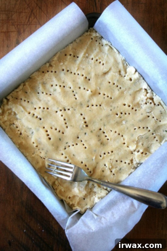 shortbread έτοιμο για το φούρνο Ένα τετράγωνο ταψί γεμάτο με ζύμη shortbread δεντρολίβανου, τρυπημένο με ένα πιρούνι.