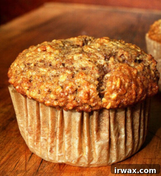 Μάφιν Βρώμης 2 Ένα αφράτο muffin βρώμης σε ξύλινο δίσκο, έτοιμο για πρωινό.