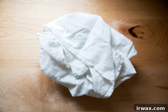 Τα Απαραίτητα για το Ψωμί με Προζύμι 5 Ένα μπολ, επενδυμένο με πετσέτα, γεμάτο με στρογγυλή ζύμη προζυμιού.