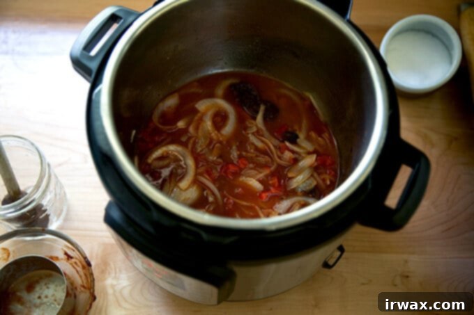 Κοτόπουλο Τίνγκα της Στιγμής 7 Μια Instant Pot που περιέχει νερό, ντομάτες, κρεμμύδια και chipotle σε σάλτσα adobo.