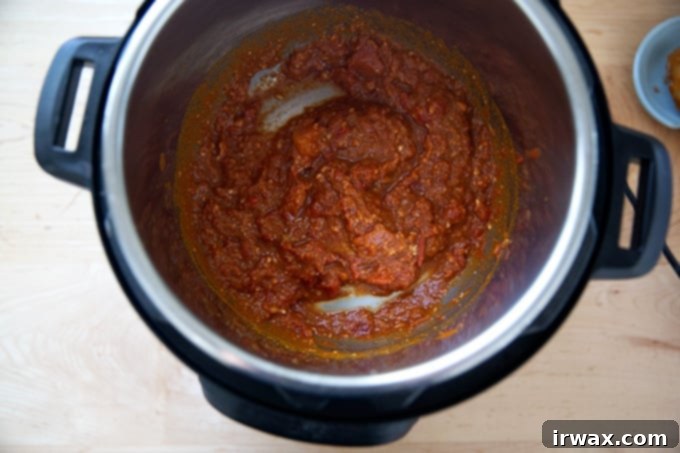 Σε Χρόνο Μηδέν: Μπάλι Τσίκεν ή Ρεβύθια 7 Μια Instant Pot γεμάτη με ντομάτες, τζίντζερ, σκόρδο, αλάτι και σκόνη κάρυ.