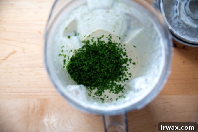 Εύκολη Βίγκαν Ranch Σως με Κάσιους 6 Σχοινόπρασο προστέθηκε σε ένα Vitamix γεμάτο με αναμεμειγμένο βίγκαν ντρέσινγκ ράντς.