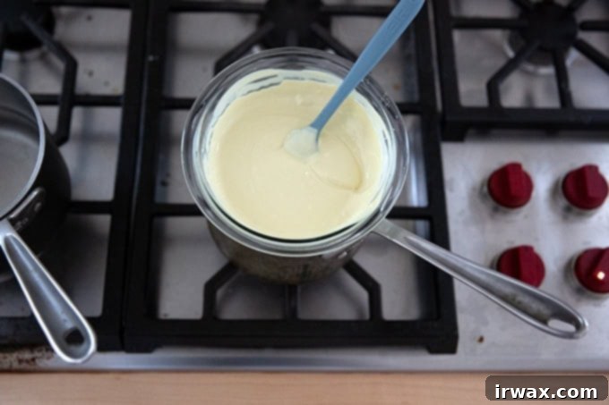 Μέντα Φλοιός με Σκόνη Μέντας 11 A bowl of melted white chocolate set over a pot on the stovetop.