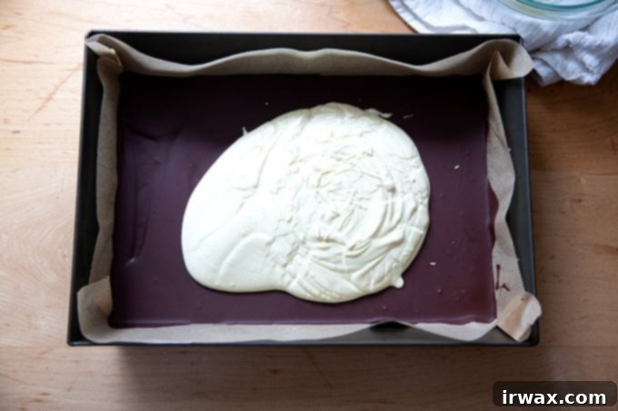 Μέντα Φλοιός με Σκόνη Μέντας 12 A layer of melted white chocolate not quite spread over a layer of dark chocolate in a 10x14-inch pan.